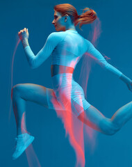 Running workout for speed, endurance. Athletic fit woman runs in colorful studio light. Motion blur, long exposure