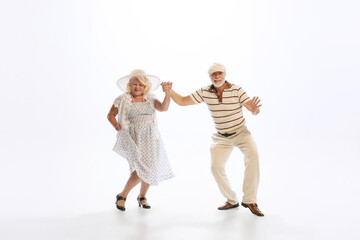 Portrait of retro style dancers, senior man and woman in vintage attire dancing swing isolated on white background. Concept of culture, art, music, style, ad