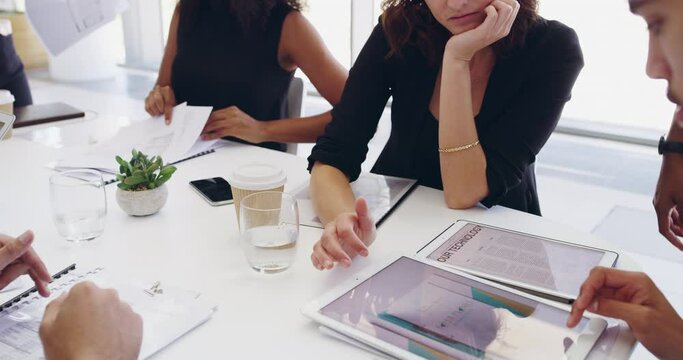 Creative design team brainstorming together with a tablet around the boardroom table during a meeting. Professional designers working on an editorial piece for a company website or magazine page