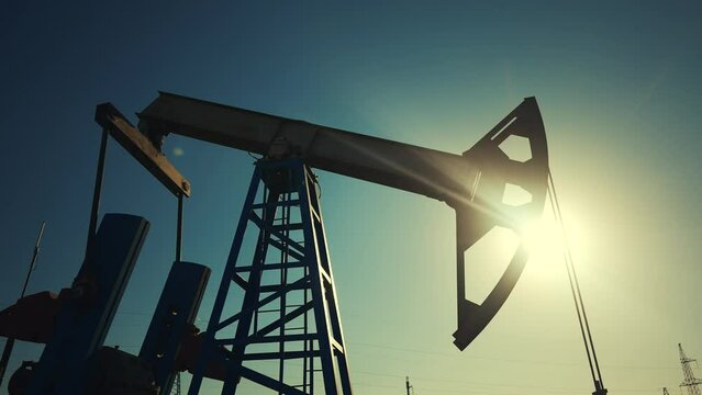 oil industry. silhouette of an oil pump extracts oil and gas from ground of the field. business industry concept lifestyle. pump pumps oil and gas at sunset. drill petroleum middle sunlight industry