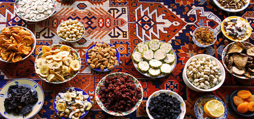 Eastern feast. Asian still life of dried fruits and nuts in plates on a carpet