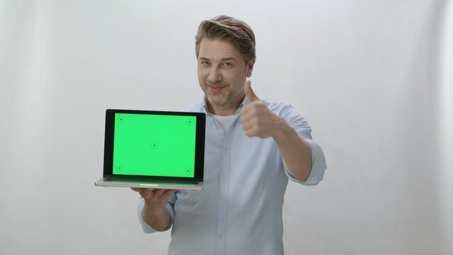 Portrait of happy businessman holding laptop with green screen. Happy businessman working on white background showing everything is perfect. You can put anything you want inside the computer.