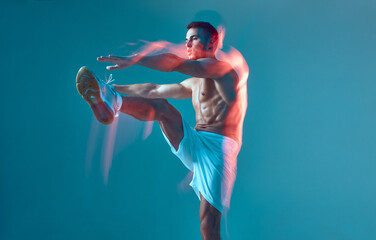 Dancing modern athletic young guy raises arms and leg performing energetic contemporary dance. Long...