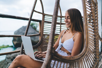 Gorgeous carefree young woman freelancer work online on laptop computer and enjoying sea view on...