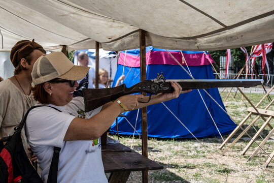 a woman tourist shoots an antique flintlock gun from the 16th century at a target