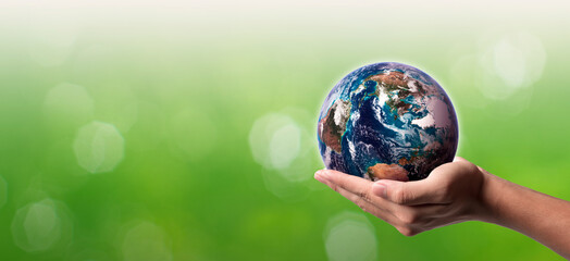 World water day. A globe in hand on green bokeh background. Elements of this image furnished by NASA