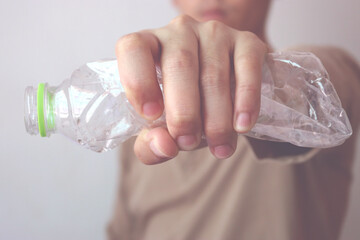 The concept of stop plastic, recycling. Man hand holding a crumpled plastic bottle. vintage style