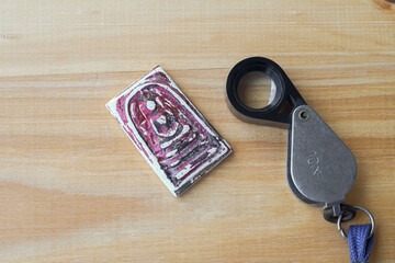 Magnifying glass for see the buddha Somdej amulet  on wood table Background.