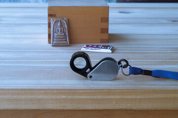 Magnifying glass for see the buddha Somdej amulet  on wood table Background.