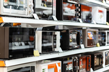 Microwave ovens stand in a row on the shelves in the supermarket