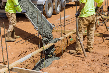 Process of pouring concrete trenches to serve as the foundation a building in construction site