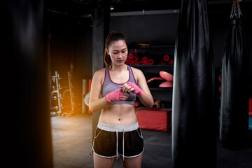 Fototapeta na wymiar Young fitness woman with sitting on boxing ring .she under wearing boxing bandage safety in boxing exercise .She exercise for strong make muscle and good healthy lifestyle.