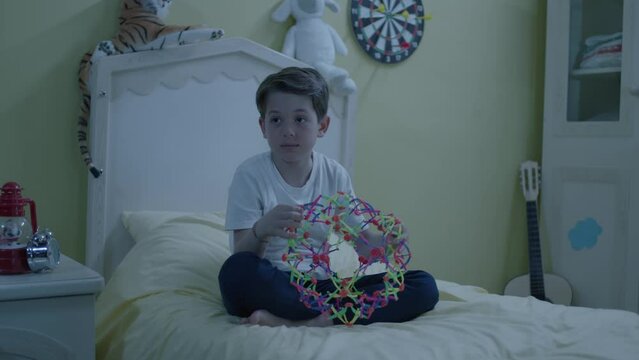 Little boy playing brain game on his bed in his room. A child playing with an intelligence-enhancing toy. A child spending time alone, studying.