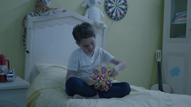 Little boy playing brain game on his bed in his room. A child playing with an intelligence-enhancing toy. A child spending time alone, studying.