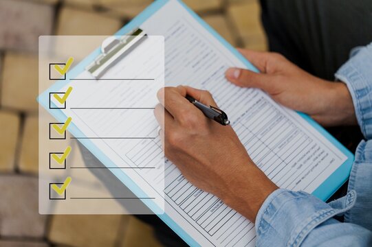An industrial or shipping inspector auditor supervisor is writing a pen to check the inventory of tasks that need to be done and has a checklist icon