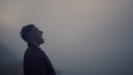 Upset guy walking on sea beach at sunrise. Exhausted man screaming outdoors