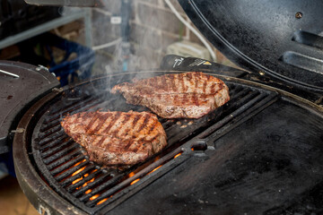 Beef blade steak grilling on barbecue grill plate . Backyard BBQ grill cooking.
