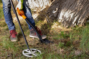 in the photo are the legs and one arm of a man who is digging the ground with a shovel in search of...