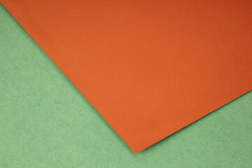 Plain orange paper sheet lying on green textured Background like an open book from top angle