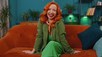 Redhead young woman in green dress laughing out loud after hearing ridiculous anecdote, funny joke,...