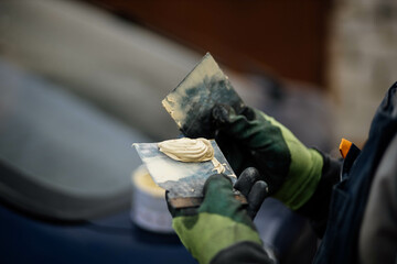 putty on a spatula by a body repair master, puttying a car body.
