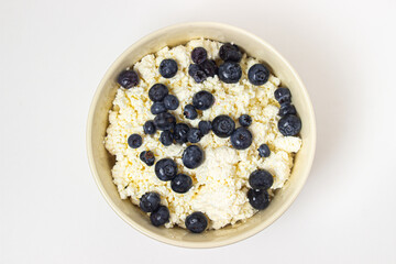Cottage cheese with blueberries on a white background. Useful and tasty breakfast.