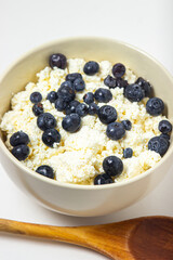 Cottage cheese with blueberries on a white background. Useful and tasty breakfast.