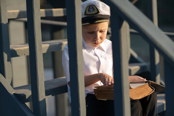 The little captain of the ship inspects the ship. Stands on the deck of a pirate ship. White shirt....