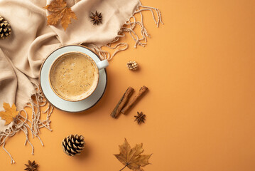 Obraz na płótnie Canvas Autumn mood concept. Top view photo of cup of frothy drinking on saucer anise cinnamon sticks yellow maple leaves scarf and pine cones on isolated orange background