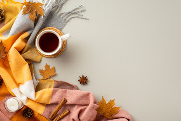Autumn inspiration concept. Top view photo of cup of tea on rattan serving mat candle cinnamon sticks anise yellow maple leaves pine cones and plaid on isolated grey background with empty space - obrazy, fototapety, plakaty