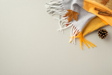 Autumn aesthetic concept. Top view photo of plaid scarf cinnamon sticks yellow maple leaf and pine cone on isolated grey background with empty space