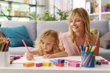 Girl and mother drawing together at home