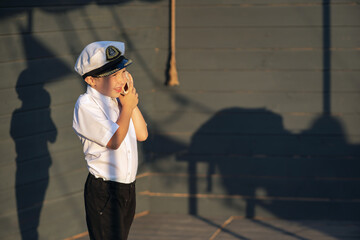 Little ship captain on the deck of a pirate ship. The boy stands on the deck of the ship with a...