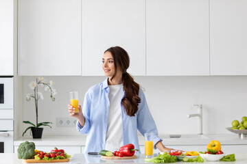 Beautiful smiling healthy woman with juice in her hands while preparing vegan food.