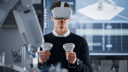 Male Student in VR Goggles Lifting and Moving Bionic Hand With Controllers While Doing His Project...