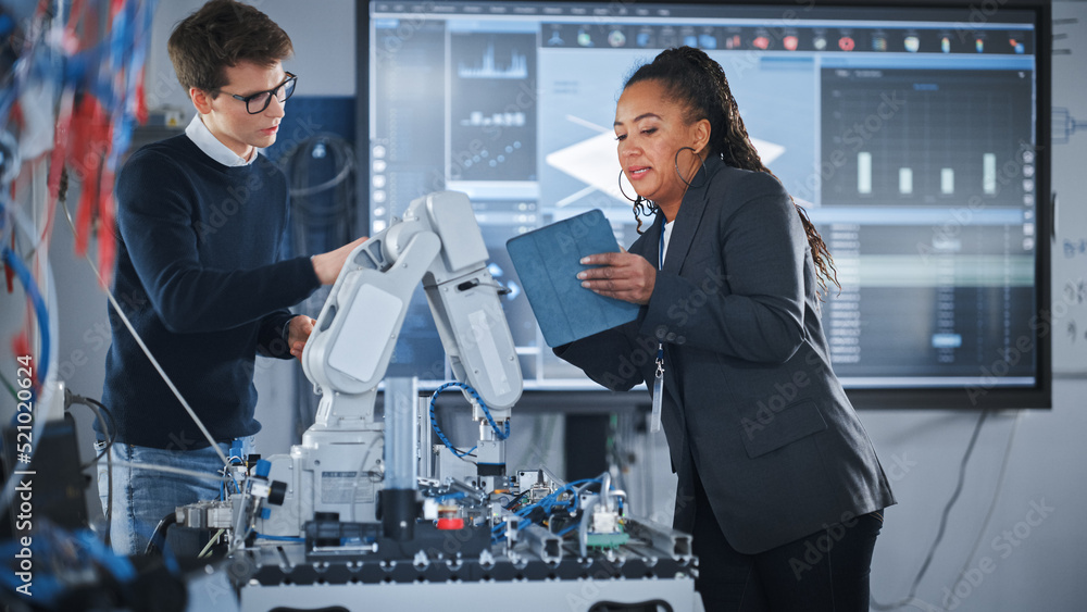 Poster black female chief engineer holding tablet and talking with male student while robot arm moving unde