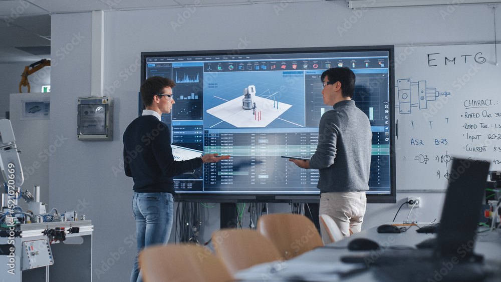 Aufkleber Diverse Team of Two Students Standing Near Big Screen with Tablet and Laptop While Discussing Programming and Technologies. Education and Studying in Modern University of Technology Concept.