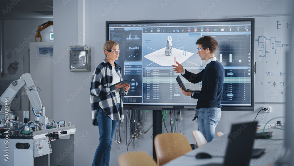 Leinwandbilder two male and female students standing near big screen and discussing program for motion of robotic a