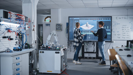 Two Male and Female Students Standing Near Big Screen and Discussing Program for Motion of Robotic...
