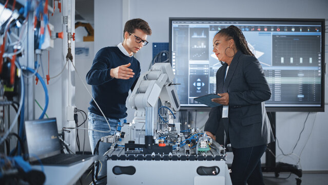 Futuristic Design of AI Robot Hand. Black Engineer Telling About Innovative Robot Arm to Students or Start-uppers. Advanced Robotics Technology for Factory Working Concept. Slow Motion.