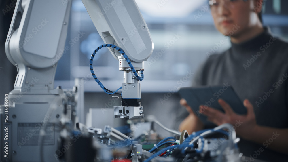 Leinwandbilder Student Holding Tablet and Controlling Robot Hand Moving at Different Ways At University Class. Asian Man Developing Software Production for Robotics Facility. Computer Science Concept. Close Up View