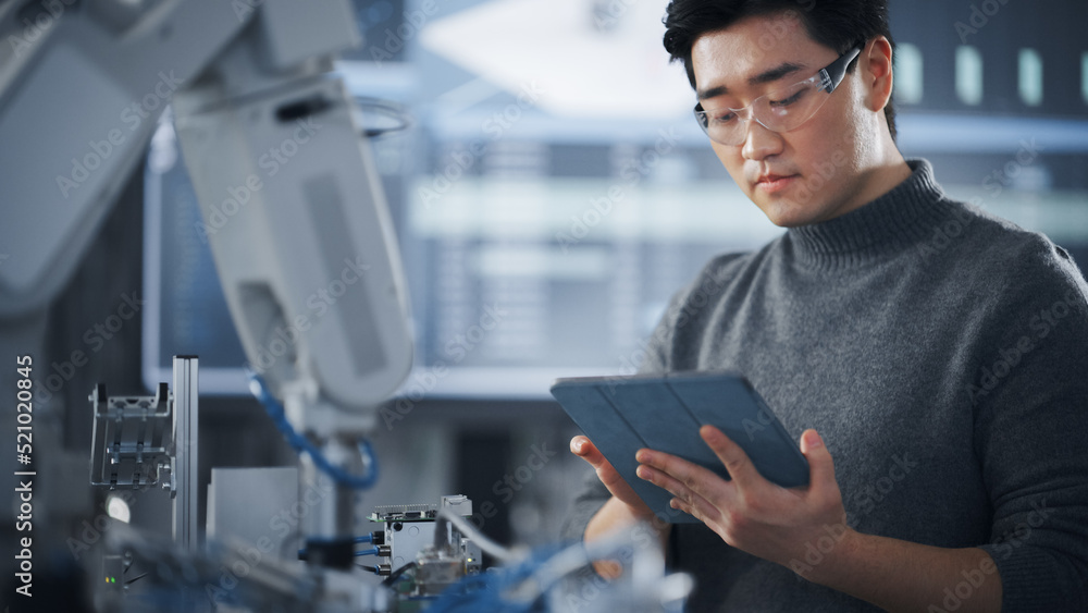 Leinwandbilder Student Holding Tablet and Controlling Robot Hand Moving at Different Ways At University Class. Asian Man Developing Software Production for Robotics Facility. Computer Science Concept. Close Up View