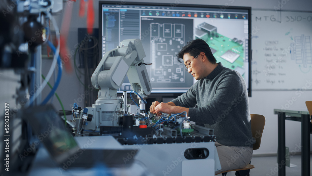 Poster Asian Male Engineer Sitting at Table Using Robot Hand and Engineering. Robot is Moving Under his Control. Education and Robotics in Modern University of Technology Class Concept.