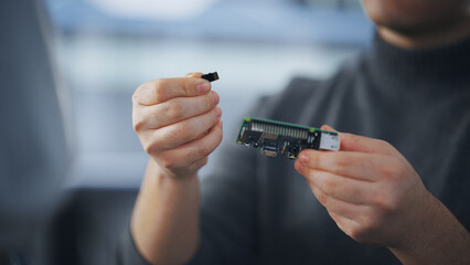 Asian Student Emamining Microchip and Takes Out Memory Card while Working on Complicated Project at Tech University. Modern Technologies, Science and Developing Concept. Close Up View.