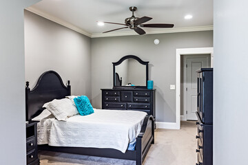 A guest bedroom in a new construction house with a dark wood bed and comforter