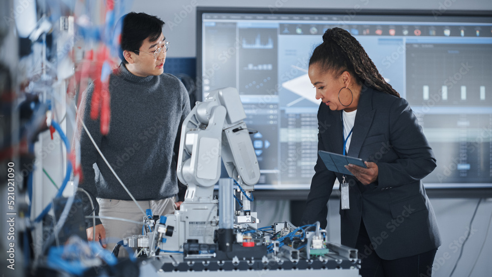 Poster teacher and engineer student meeting in robotic research laboratory: they gathered around table, tal