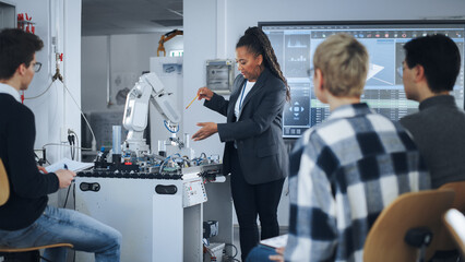 Black Teacher and Diverse Group of Young Students Brainstorming at University Robotics Class. People Discussing with their Educator while Using Robot Arm. Computer Science Education, Design, Learn.