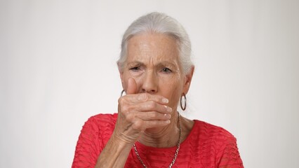 Portrait of pretty elderly woman coughing on solid white background.