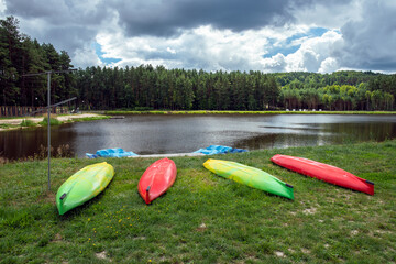 Inverted water kayaks lying on the shore of the lake on the grassy beach. Jacnia, Roztocze, Poland