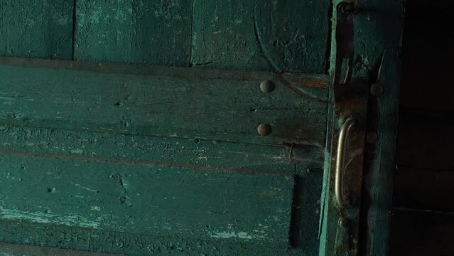 vintage retro door with a large wooden handle and decorative elements in an abandoned house is covered with green red that is peeling off